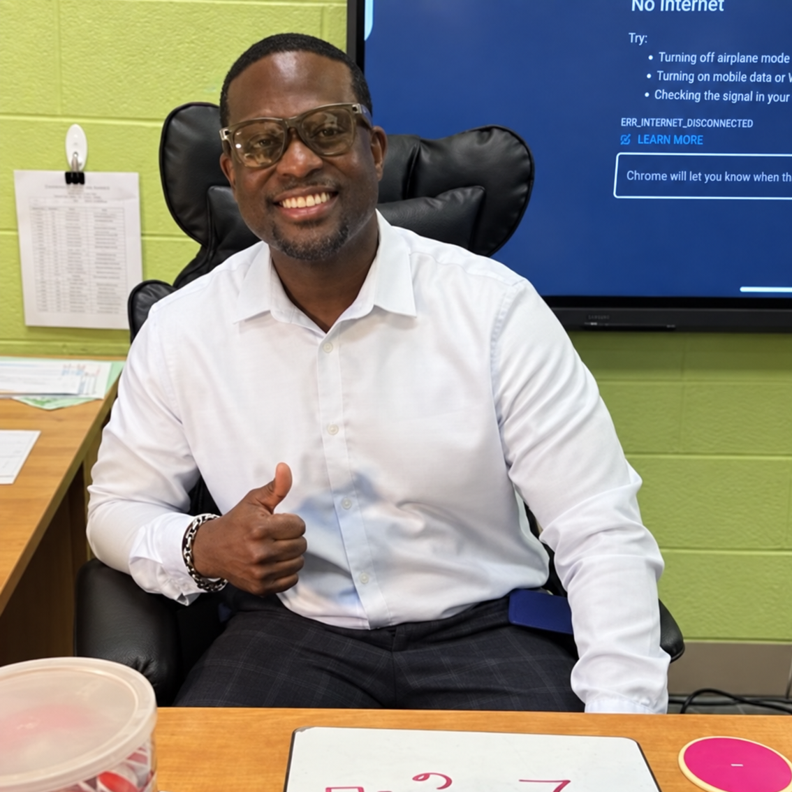llwood School Principal Ed Davies smiles while seated at a classroom table.