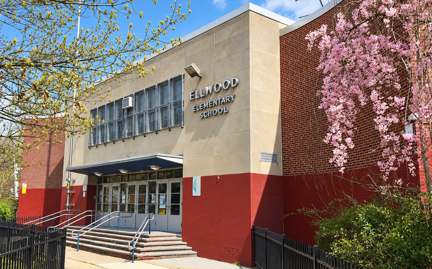 Entrance to Ellwood Elementary School, framed by trees with pink spring blossoms.